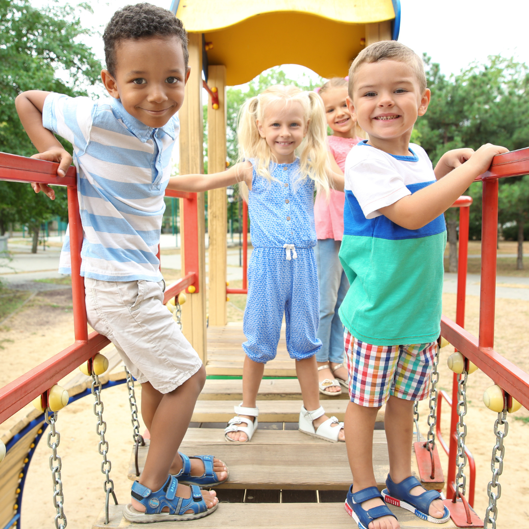 four children pose on climbing playground